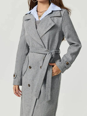 Gray trench coat worn by a person on a white background