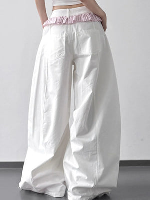 White wide-leg pants with a pink waistband on a plain background