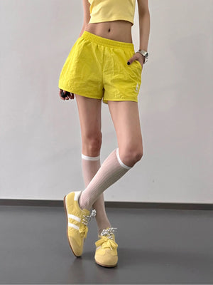 Person wearing yellow shorts and shoes on a plain background