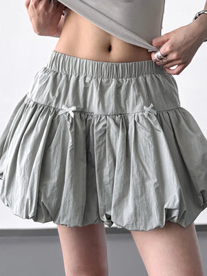 Person wearing a light gray skirt with a plain background
