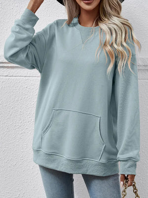 Light blue sweatshirt worn by a person against a white wall