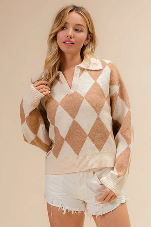 Woman wearing a beige and white argyle sweater with denim shorts on a beige background