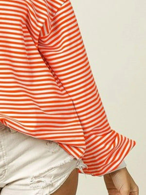 Close-up of a person wearing an orange and white striped shirt with a neutral background