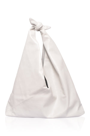 A woman wearing a black knotted leather shoulder bag with a geometric patterned dress.