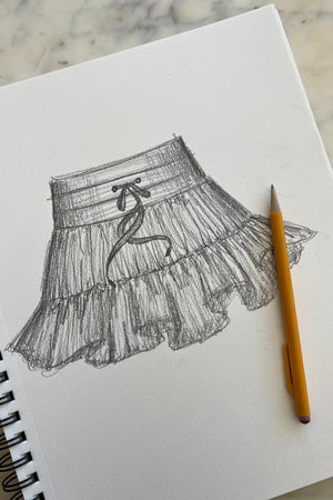 Sketch of a ruffled skirt on a notebook with a pencil next to it