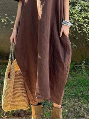 Person wearing a brown dress holding a yellow woven bag outdoors.