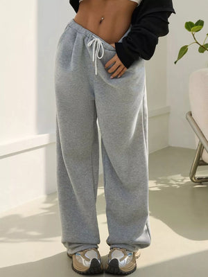 Person wearing gray sweatpants in a minimal indoor setting