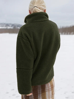 Person wearing a green jacket in a snowy landscape