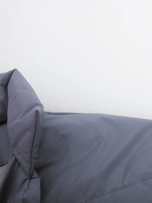 Gray comforter on a bed with a white background
