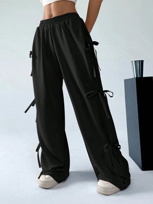Black wide-leg pants with drawstrings worn by a person on a light gray background