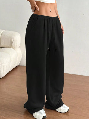 Person wearing black wide-leg pants with a neutral background