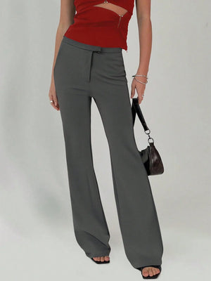 Person wearing gray wide-leg pants and a red top on a plain background
