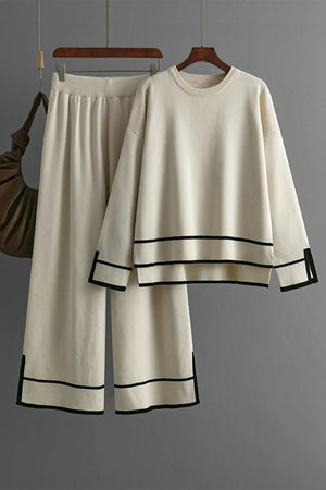 White outfit with black trim on a hanger against a gray background