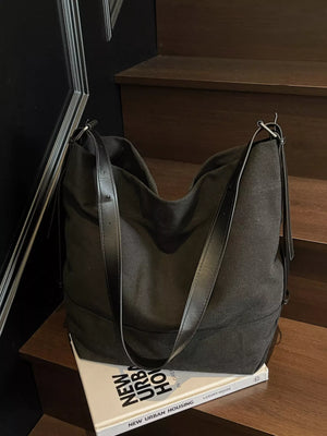 Dark green handbag on a wooden surface with a book underneath