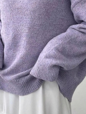 Close-up of a person wearing a light purple sweater with a neutral background