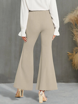 Beige flared pants worn with a white blouse against a gray background
