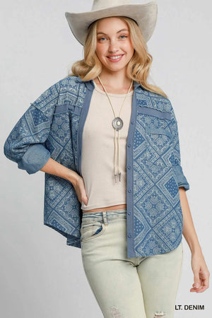 Woman wearing a blue patterned denim jacket, beige top, light green jeans, and a beige cowboy hat on a white background.