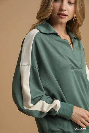 Green and white long-sleeve top worn by a person on a beige background
