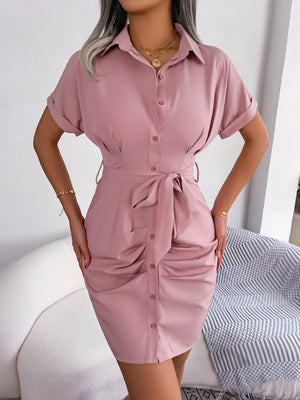 Woman wearing a pink shirt dress in a minimal indoor setting
