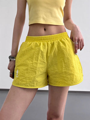 Person wearing bright yellow shorts and a cropped top on a plain background