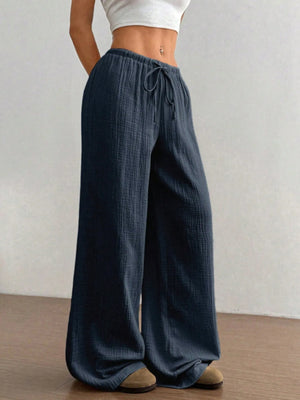Person wearing wide-leg jeans with a plain background