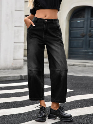 Person wearing black wide-leg jeans and black shoes on a city street.