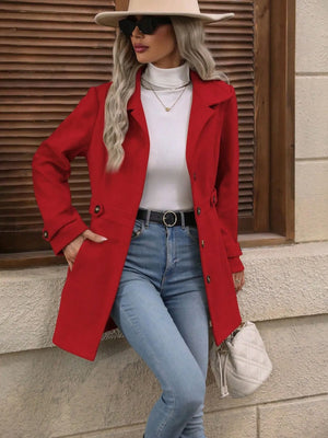 Woman wearing a red coat, white top, blue jeans, and beige hat against a wooden background.