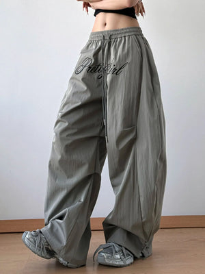 Person wearing gray wide-leg pants with 'PrettyGirl' text on a plain background