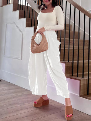 Woman in a white outfit holding a woven handbag on a staircase.