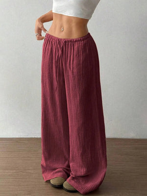 Person wearing maroon wide-leg pants with a plain background