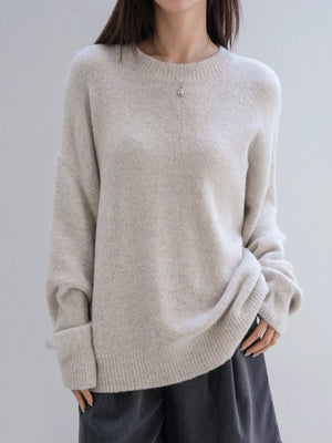 Person wearing a beige sweater against a plain background