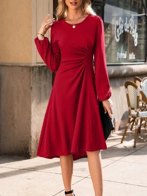 Woman wearing a red dress standing on a sidewalk with a cafe in the background