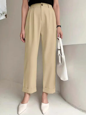 Person wearing beige pants with a white handbag against a neutral background