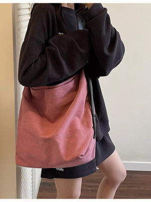 Person wearing a black hoodie and pink bag with a neutral background