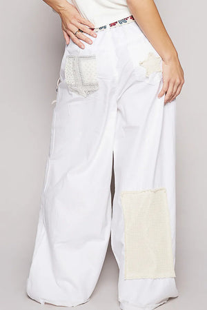 White wide-leg jeans with patchwork design on a plain background