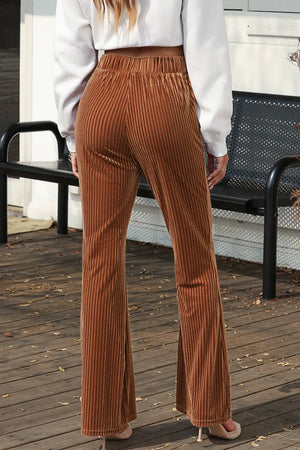Person wearing brown ribbed flared pants on a wooden deck.