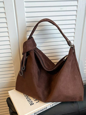 Brown handbag on a book with a window blind background