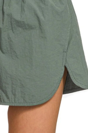 Green shorts worn by a person on a white background