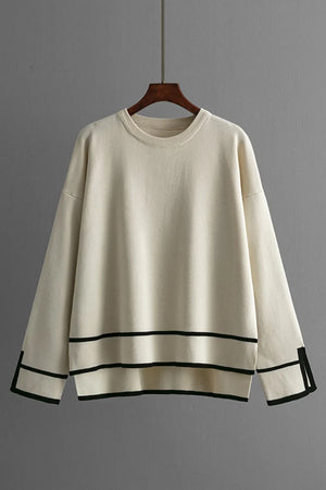 Beige sweater with black trim on a wooden hanger against a gray background