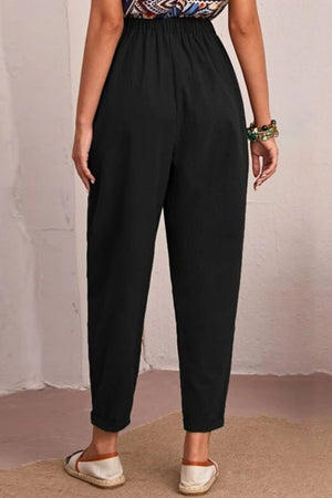 Person wearing black pants with a plain background