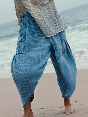 Person wearing blue checkered pants and a striped shirt on a beach.