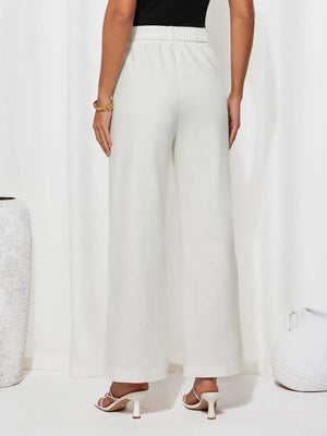 Person wearing white wide-leg pants on a plain background
