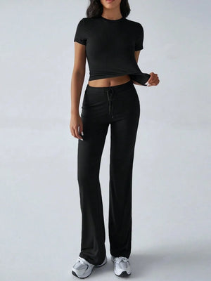 Person wearing a black crop top and black pants on a white background