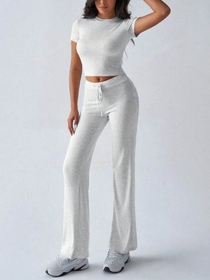 Person wearing a white crop top and light gray sweatpants on a white background