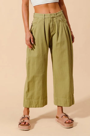 Person wearing green wide-leg pants on a beige background