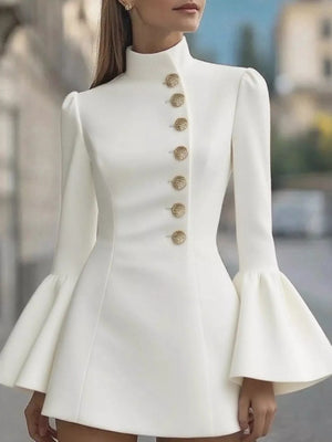 White dress with gold buttons and flared sleeves worn by a model outdoors.