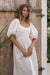 Model standing by a gate showing view of Cherie Puff Sleeve Midi dress- white