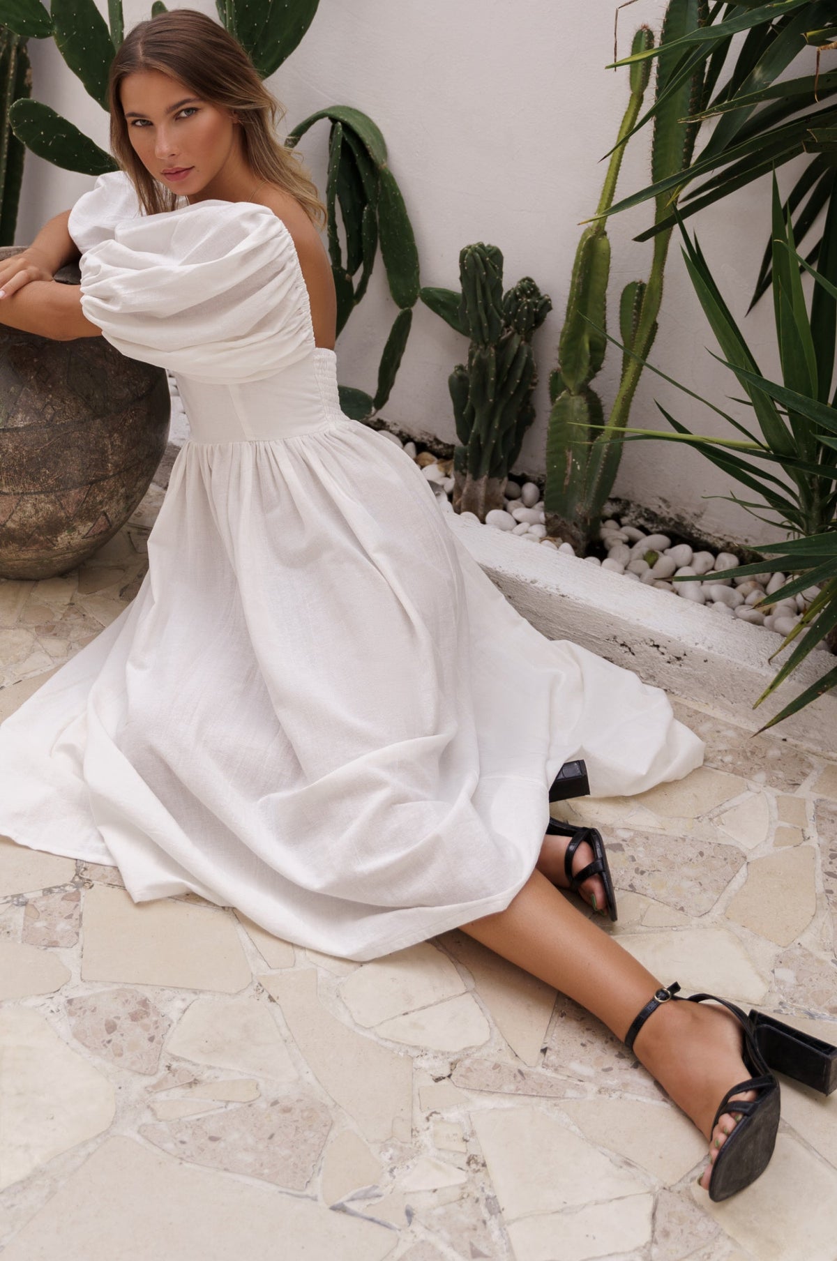 Model sitting sideways showing Cherie Puff Sleeve Midi dress- white