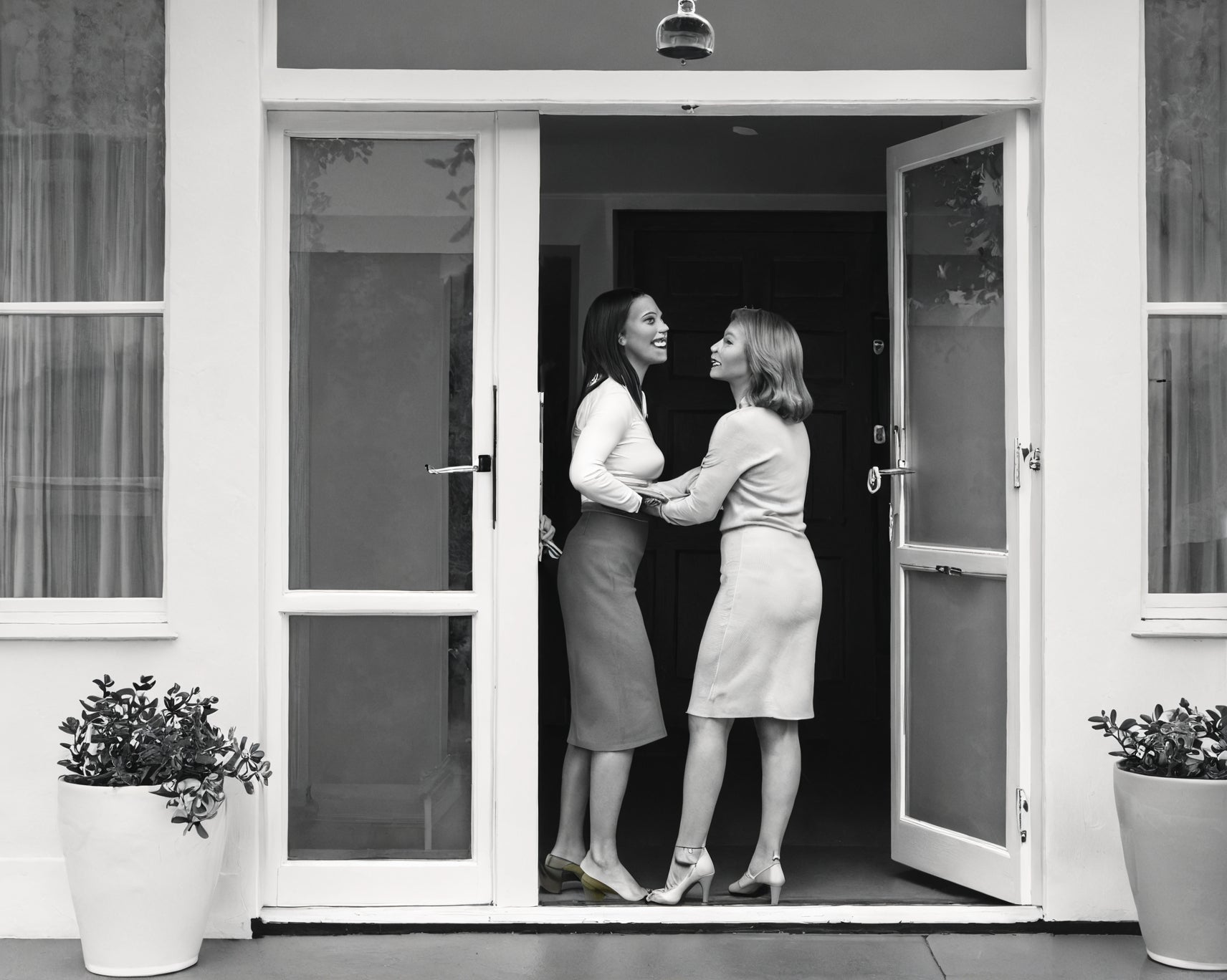 One woman is greeting the other at the door