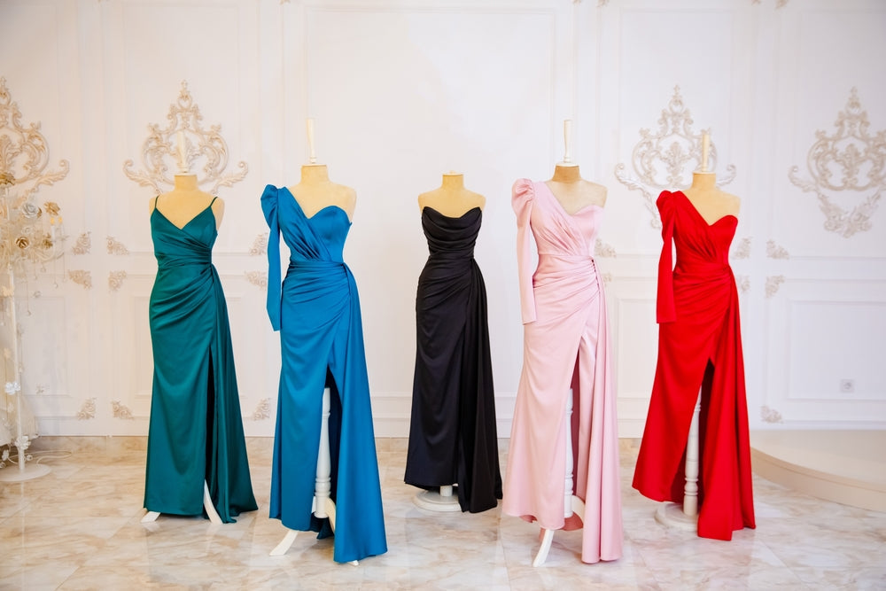 A picture of five formal dresses from the left is green, blue, black, pink and red